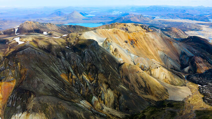 Aerial view of a snowed mountain range and colored mountains in the highlands of Landmannalaugar, Iceland.