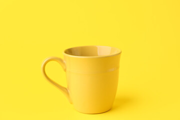Yellow ceramic cup on color background