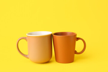 Brown ceramic cups on yellow background