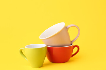 Different ceramic cups on yellow background