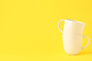 White ceramic cups on yellow background