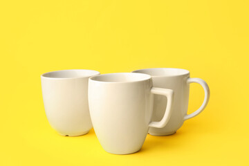 White ceramic cups on yellow background