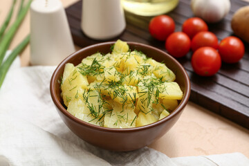 Bowl of tasty potato salad with dill on beige background