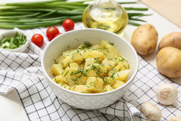 Bowl of tasty potato salad with dill, tomatoes and mushrooms on white wooden background