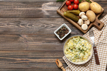 Bowl of tasty potato salad with vegetables and peppercorns on wooden background