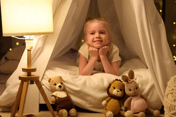 Cute little girl lying in hut at home