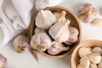 Wooden bowls with fresh garlic and cloves on white background