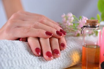 Close-up of woman’s hands with red nail polish on a towel in a beauty salon. Manicure and beauty concept