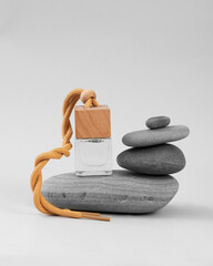 car perfume in a glass bottle with a wooden cap in a composition with stones on a light background