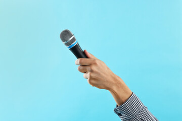 Man with microphone on light blue background, closeup