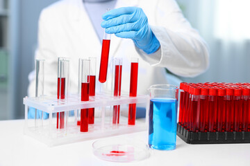 Laboratory testing. Doctor taking test tube with blood sample from rack indoors, closeup