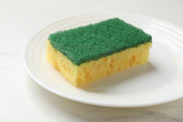 Soft sponge and plate on white table, closeup