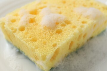 Yellow sponge with foam on plate, closeup