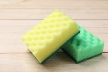 Two soft sponges on wooden table, closeup