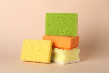 Different colorful sponges on beige background, closeup