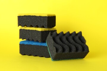 Different clean sponges on yellow background, closeup