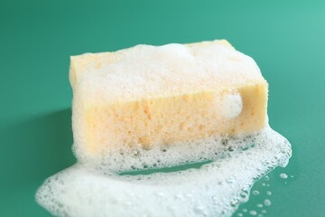 Sponge with foam on green background, closeup