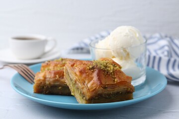 Tasty baklava with chopped nuts and scoops of ice cream on white table, closeup