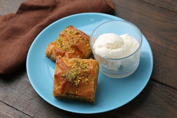 Tasty baklava with chopped nuts and scoops of ice cream on wooden table, closeup