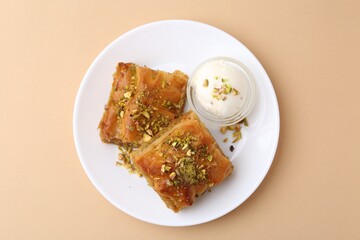 Tasty baklava with chopped nuts and scoop of ice cream on beige table, top view
