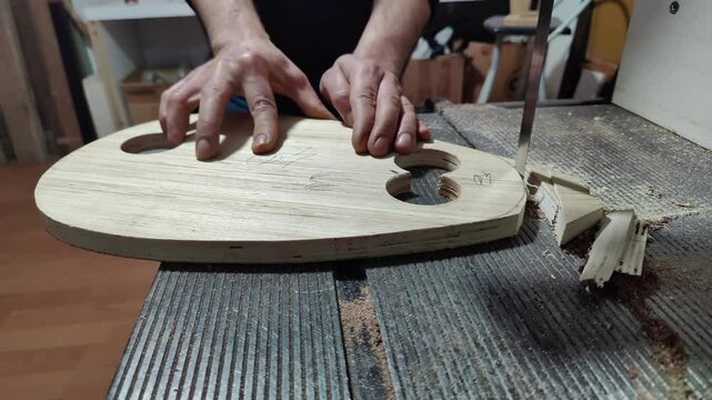 Musical Instrument Maker Cuts Wooden Body with Band Saw Footage.