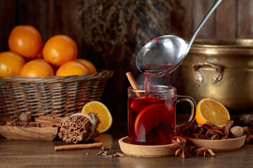 Mulled wine is poured into a glass cup.
