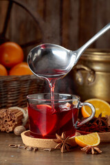 Mulled wine is poured into a glass cup.