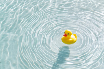 Yellow rubber duck floating in clear water with gentle ripples