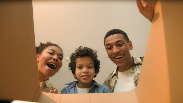 Point of view POV opening inside cardboard box happy surprised joyful African american family parents son little boy child kid order delivery unboxing unpacking parcel online shopping store moving day
