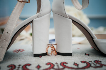 Elegant Wedding Rings Nestled Between White High Heels
