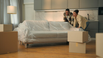 Happy satisfied couple home owners moving in new house relocation African American family move couch buy furniture sofa delivery woman man in love affection hugging real estate mortgage bank credit