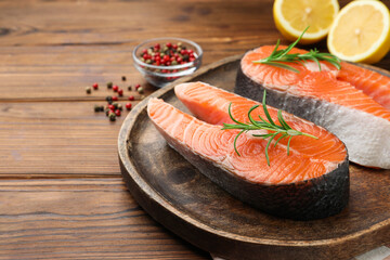 Fresh raw salmon steaks and spices on wooden table, closeup
