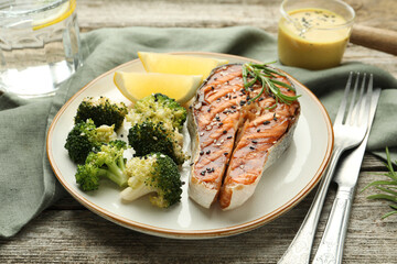 Tasty grilled salmon steak with broccoli served on wooden table, closeup