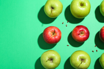 Flat lay composition with different apples and seeds on green background. Space for text