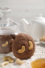 Tasty chocolate cookies with cashew on wicker mat, closeup