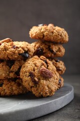 Delicious oatmeal cookies with raisins and nuts on grey table, closeup