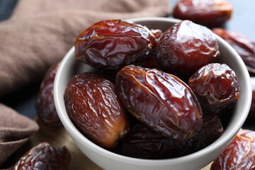 Many tasty dried dates in bowl on table, closeup