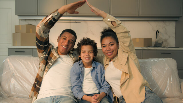 African American happy smiling parents little son boy child kid family bonding make roof with hands symbol home dream moving day relocation buy rental new house real estate insurance mortgage credit