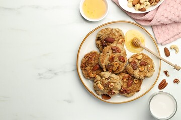 Tasty cookies with nuts, honey dipper and milk on white marble table, flat lay. Space for text