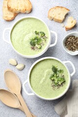Delicious broccoli cream soup served on light table, flat lay