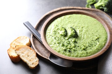 Delicious broccoli cream soup served on grey table, closeup
