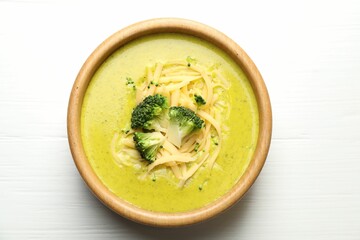 Delicious broccoli cream soup in bowl on white wooden table, top view