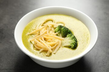 Delicious broccoli cream soup in bowl on gray textured table, closeup