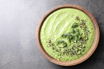 Delicious broccoli cream soup in bowl on grey table, top view. Space for text