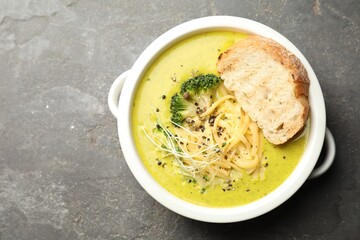 Delicious broccoli cream soup and crouton in bowl on gray textured table, top view. Space for text