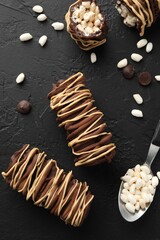 Delicious chocolate puffed rice bars and spoon on dark gray textured table, flat lay