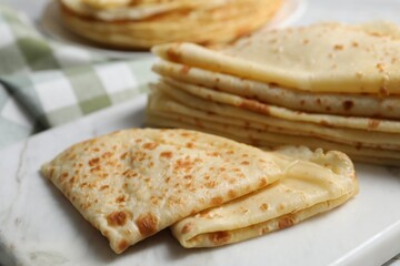 Many tasty thin crepes on table, closeup