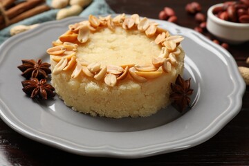 Delicious semolina halva with almond flakes and spices on wooden table, closeup