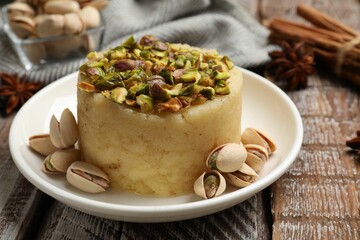 Delicious sweet semolina halva with pistachios and spices on wooden table, closeup