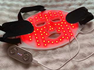 Led light therapy face mask on soft fabric, above view. Beauty treatment